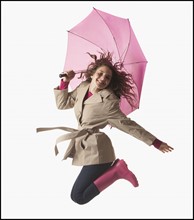 Woman with umbrella jumping on white background. Photo : Mike Kemp