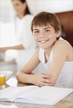 Boy (12-13) sitting over homework with glass of orange juice. Photo : Momentimages