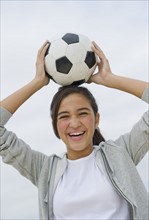 Portrait of girl (12-13) holding soccer ball.