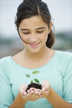 Girl (12-13) holding seedling.