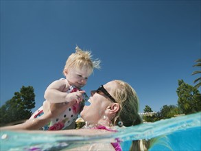 Mother and daughter (12-18months) playing at swimming pool.