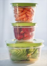 Carrots, strawberries and salad in plastic containers, studio shot. Photo : Jamie Grill
