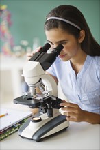 Schoolgirl (12-13) using microscope.