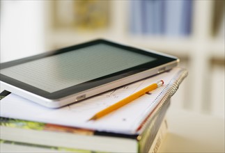 Digital tablet on stack of books.