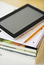 Digital tablet on stack of books.