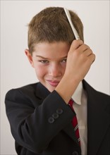 Boy (10-11) in suit combing hair. Photo : Daniel Grill