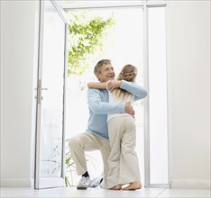 Granddaughter (10-11) and grandfather hugging in doorway. Photo : Momentimages
