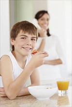 Boy (12-13) with dessert and glass of range juice. Photo : Momentimages