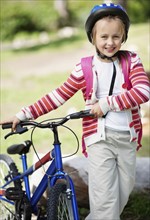 Smiling girl (10-11) with bicycle. Photo : Momentimages