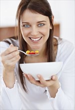 Portrait of mid adult woman eating from bowl. Photo : Momentimages