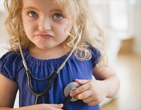 Portrait of blond girl (4-5) with stethoscope. Photo : Jamie Grill