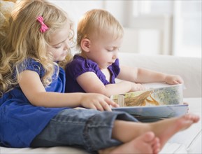 Two blond girls (20months, 4-5) reading book. Photo : Jamie Grill