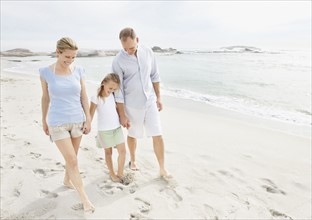 Girl (10-11) playing on beach with parents. Photo : Momentimages