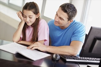 Father helping daughter (10-11) do homework. Photo : Momentimages