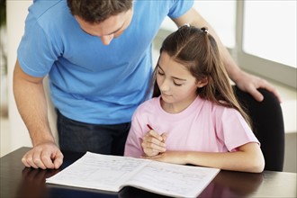 Father helping daughter (10-11) do homework. Photo : Momentimages