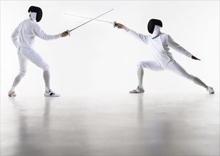 Studio shot of fencers in attacking lunge.