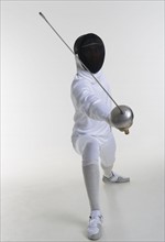 Studio portrait of fencer holding fencing foil.