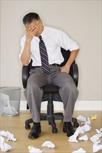 Stressed businessman sitting in office. Photo : Jamie Grill