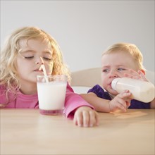 Two blond girls (20months, 4) drinking milk. Photo : Jamie Grill