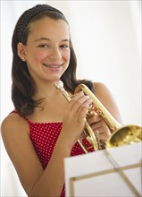 Portrait of girl (12-13) with trumpet looking at camera. Photo : Daniel Grill
