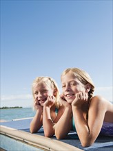 Girls (6-7-7,8-9) resting on raft on lake.
