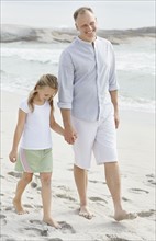 Girl (10-11) playing on beach with father. Photo : Momentimages