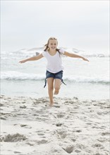 Portrait of girl (10-11) running on beach. Photo : Momentimages