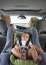 Young family with small girl (12-18 months) sitting in car.