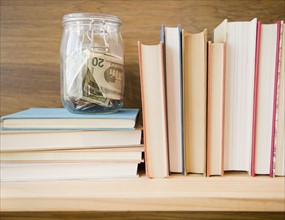 Row of books and jar with savings. Photo : Jamie Grill