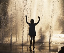 Silhouette of girl playing in fountain. Photo : fotog