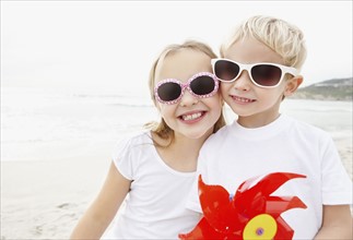 Portrait of brother (4-5) and sister (10-11) wearing sunglasses on beach. Photo : Momentimages