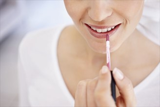 Close-up of woman applying lipstick. Photo : Momentimages
