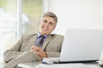 Portrait of cheerful businessman with laptop. Photo : Momentimages