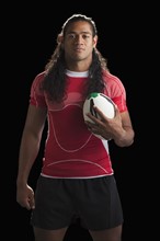Studio portrait of male rugby player holding ball. Photo : Mike Kemp
