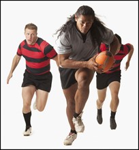 Rugby player running with ball, team chasing. Photo : Mike Kemp