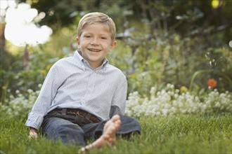Portrait of boy (6-7) sitting on grass. Photo : FBP