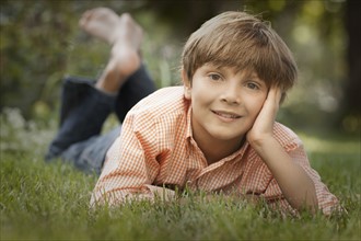 Portrait of boy (8-9) lying on grass. Photo : FBP