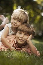Portrait of brother and sister (2-8-9) lying on grass. Photo : FBP