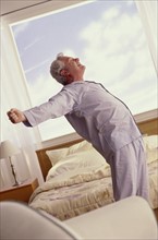 Senior man stretching in his bedroom. Photo : Fisher Litwin