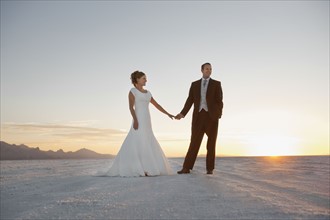 Bride and groom holding hands in desert. Photo : FBP