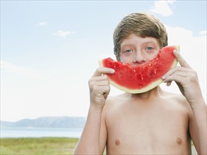 Boy (12-13) eating watermelon.
