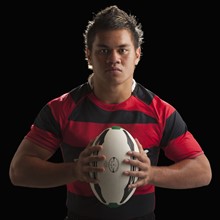 Studio portrait of male rugby player holding ball. Photo : Mike Kemp