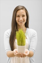 Studio portrait of young woman holding wheat grass. Photo : FBP