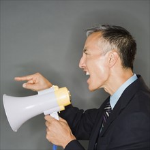Businessman shouting with megaphone, studio shot. Photo : Jamie Grill