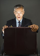 Surprise businessman looking into open briefcase, studio shot. Photo : Jamie Grill
