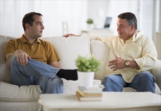 USA, New Jersey, Jersey City, Father and son talking on sofa in living room.