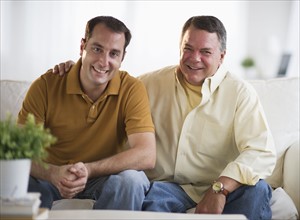 USA, New Jersey, Jersey City, Portrait of father and son sitting on sofa in living room.
