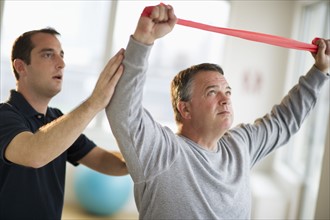USA, New Jersey, Jersey City, Fitness instructor assisting man in gym.