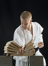 Young man breaking boards with karate chop on black background.