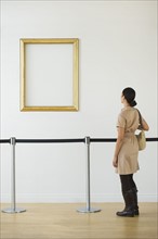 Woman looking at blank picture frame in art gallery.